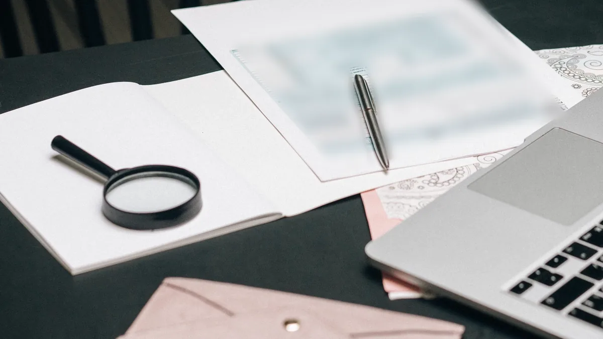 Dossier à examiner, loupe et ordinateur sur un bureau